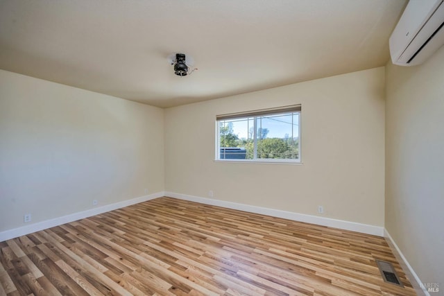 unfurnished room with light hardwood / wood-style flooring and a wall mounted AC