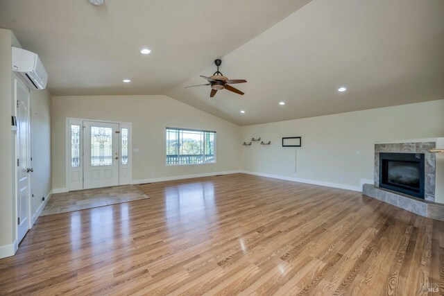19316 N Shore Ct, Hidden Valley Lake, CA 95467 - unfurnished living room with a wall mounted air conditioner, a high end fireplace, light wood-style floors, ceiling fan, and lofted ceiling