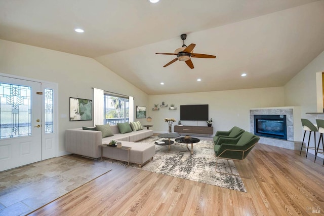 living room with light wood-type flooring, high vaulted ceiling, ceiling fan, and a premium fireplace