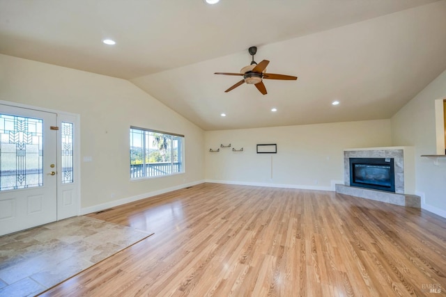 unfurnished living room featuring a fireplace, ceiling fan, light hardwood / wood-style flooring, and lofted ceiling