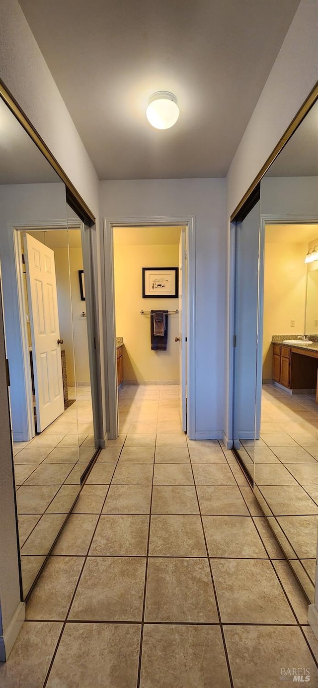 corridor with light tile patterned floors and sink