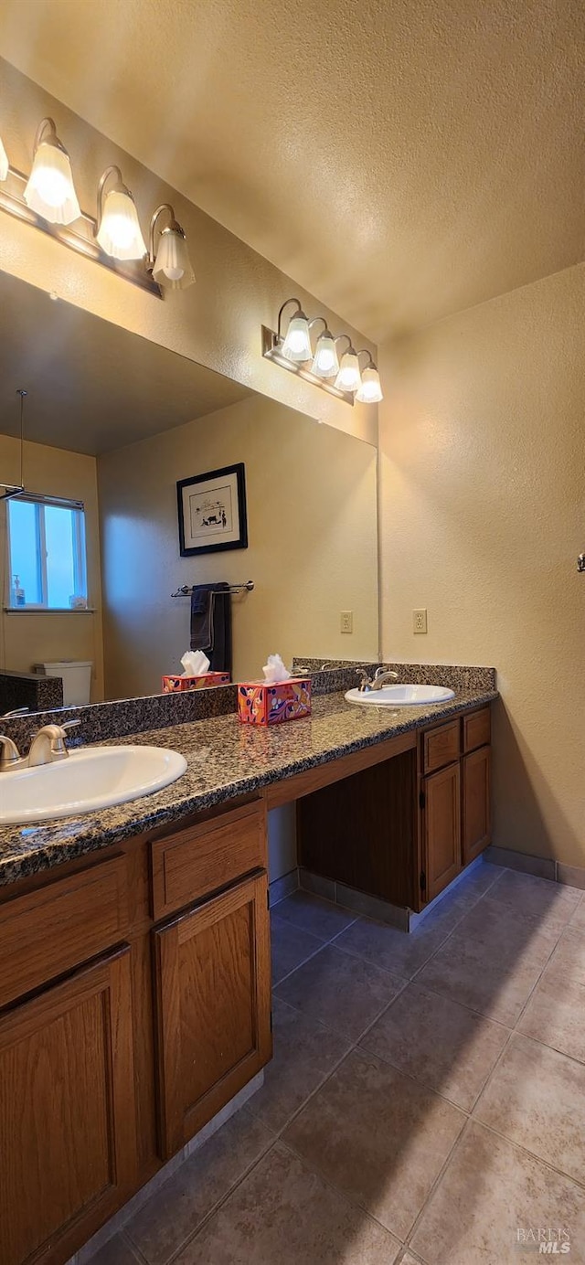 bathroom with vanity, a textured ceiling, and tile patterned flooring