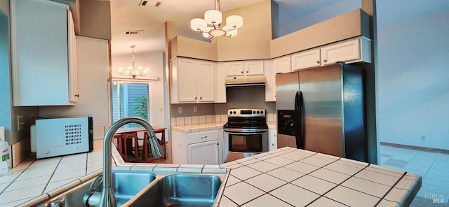 kitchen featuring tile countertops, white cabinets, decorative light fixtures, appliances with stainless steel finishes, and a notable chandelier