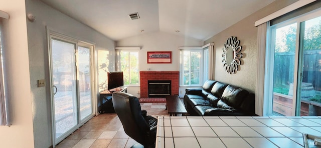 tiled living room with a brick fireplace, vaulted ceiling, and a healthy amount of sunlight