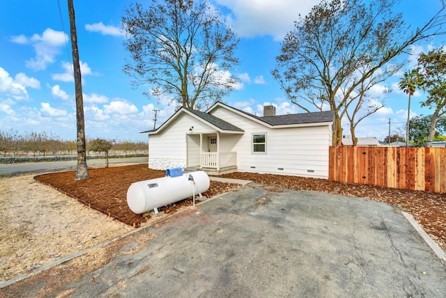 view of front of home featuring a shingled roof, crawl space, a chimney, and fence