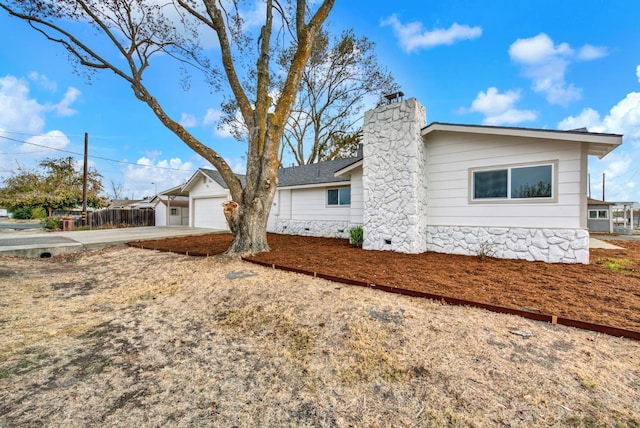 exterior space featuring a garage, concrete driveway, crawl space, and a chimney