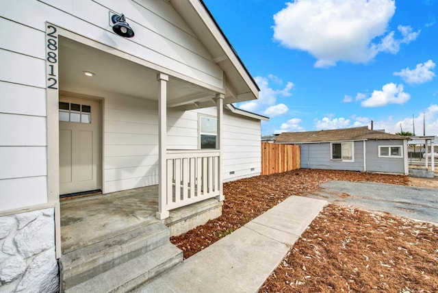 entrance to property with a porch and fence