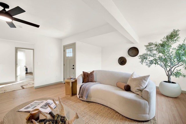 living area with light wood finished floors, baseboards, a ceiling fan, and beamed ceiling