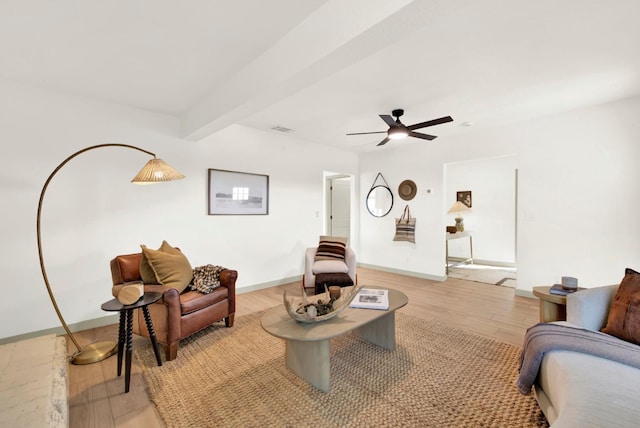 interior space featuring light wood finished floors, baseboards, visible vents, a ceiling fan, and beam ceiling