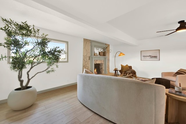 living room with light wood-style flooring, baseboards, ceiling fan, and a high end fireplace