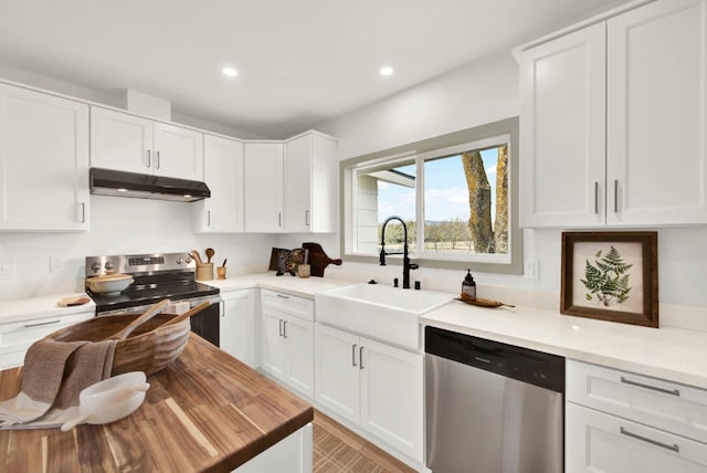 kitchen featuring white cabinets, stainless steel appliances, under cabinet range hood, a sink, and recessed lighting