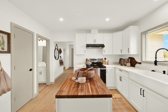 kitchen featuring under cabinet range hood, a sink, wood counters, a center island, and stainless steel range with electric stovetop