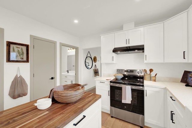 kitchen featuring stainless steel electric range oven, butcher block counters, white cabinetry, and under cabinet range hood