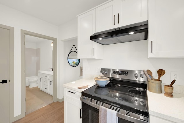 kitchen with electric range, light wood-style flooring, white cabinets, and under cabinet range hood