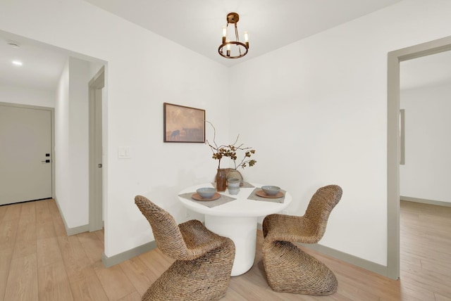 dining space featuring light wood-style floors, baseboards, and a chandelier