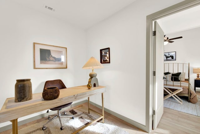 office space with visible vents, ceiling fan, baseboards, and wood finished floors