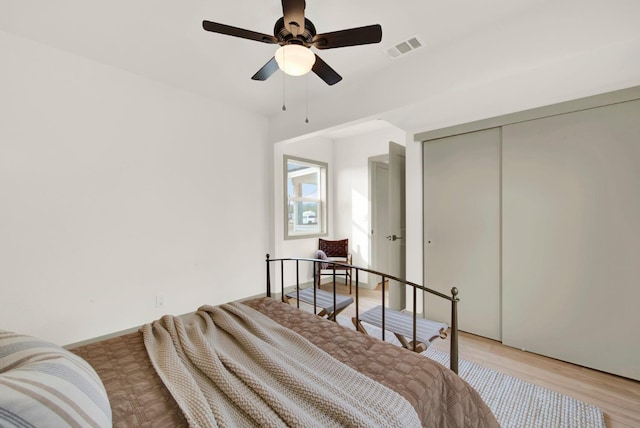 bedroom with a closet, visible vents, ceiling fan, and light wood finished floors