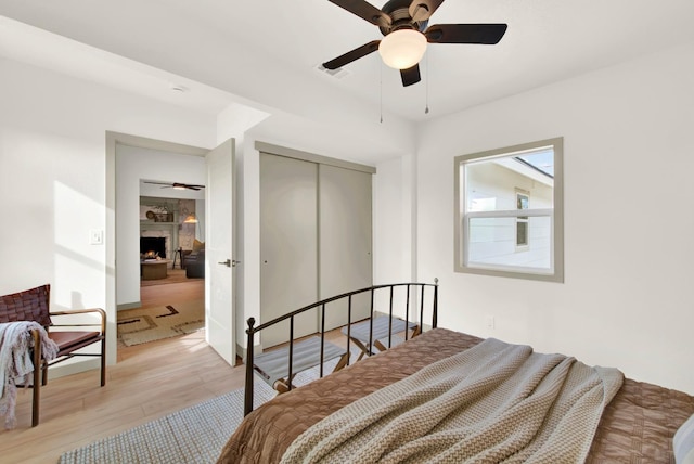 bedroom with a closet, light hardwood / wood-style flooring, and ceiling fan