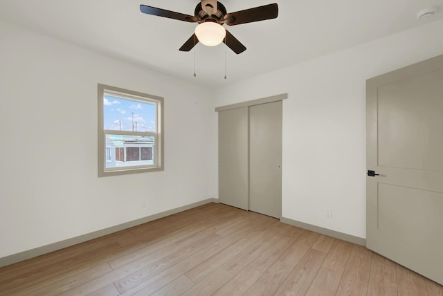 unfurnished bedroom featuring light wood-style floors, a closet, ceiling fan, and baseboards