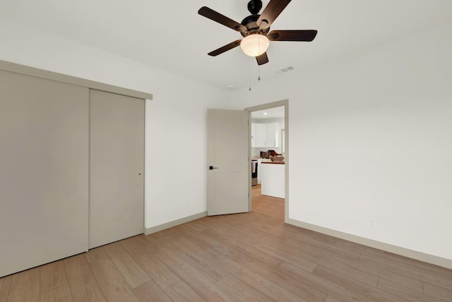 unfurnished bedroom with light wood finished floors, baseboards, visible vents, ceiling fan, and a closet