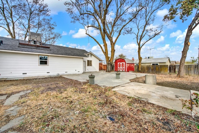 view of yard with a patio area, a fenced backyard, a storage shed, and an outbuilding