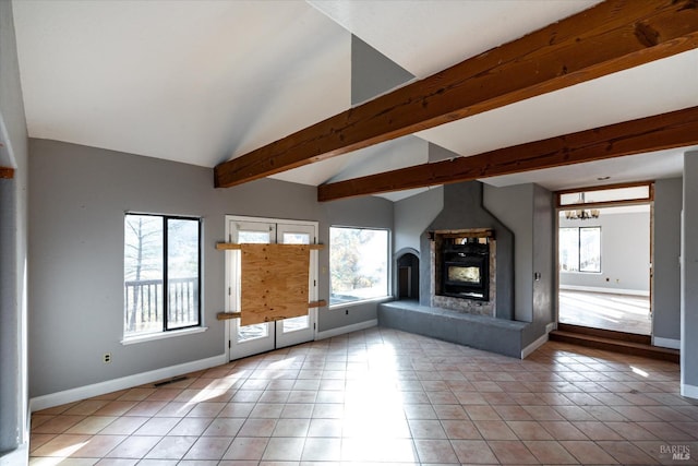 unfurnished living room featuring vaulted ceiling with beams, a healthy amount of sunlight, and light tile patterned flooring