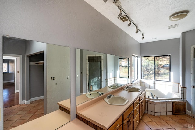 bathroom with tile patterned floors, separate shower and tub, track lighting, a textured ceiling, and vanity