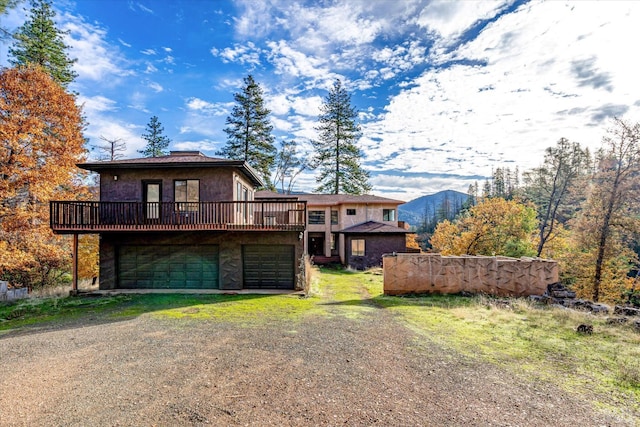 back of house with a garage and a deck with mountain view