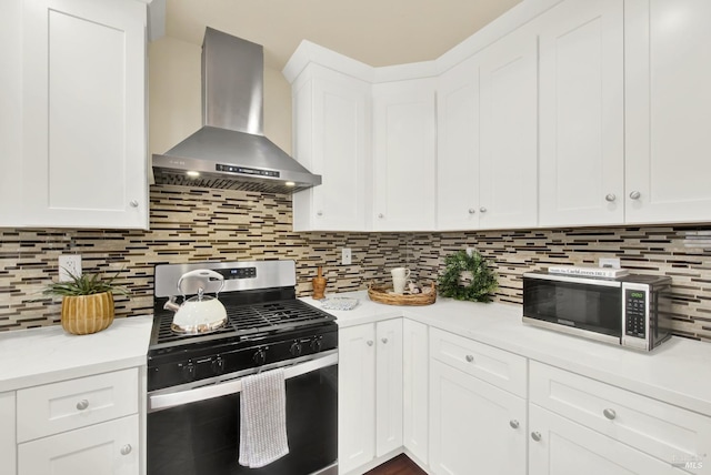 kitchen with white cabinets, wall chimney exhaust hood, backsplash, and appliances with stainless steel finishes