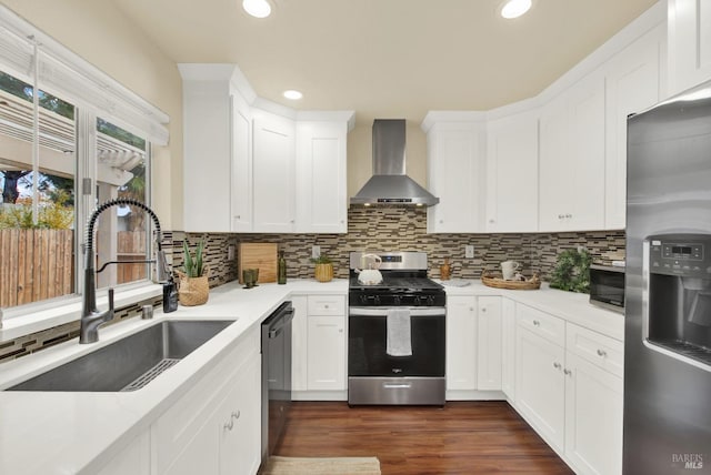 kitchen featuring appliances with stainless steel finishes, wall chimney exhaust hood, sink, white cabinets, and dark hardwood / wood-style floors