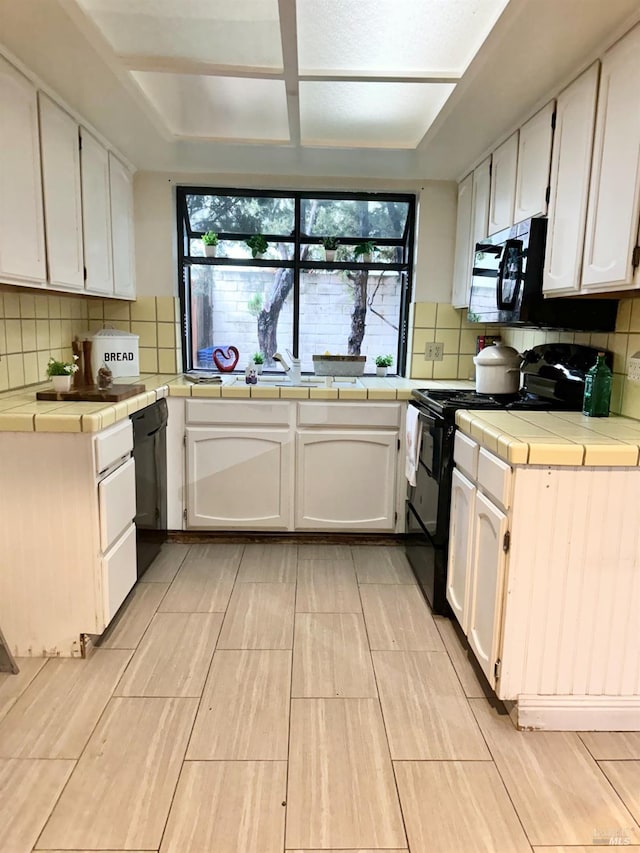 kitchen with white cabinets, tasteful backsplash, black appliances, and tile countertops