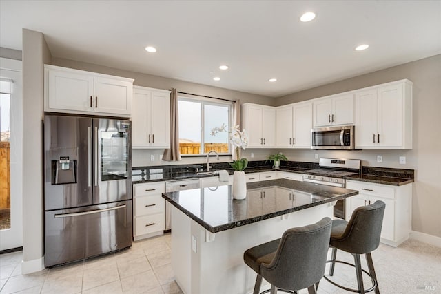 kitchen featuring sink, light tile patterned floors, white cabinets, a kitchen island, and appliances with stainless steel finishes