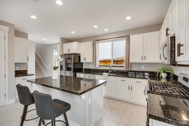 kitchen featuring white cabinets, stainless steel appliances, and dark stone countertops