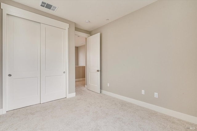 unfurnished bedroom featuring light carpet and a closet