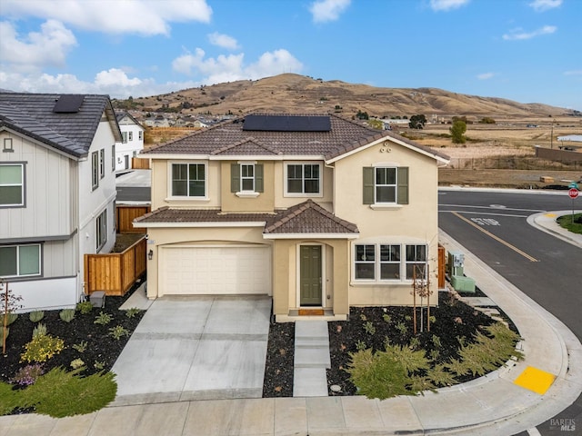 view of front of property featuring a mountain view, a garage, and solar panels