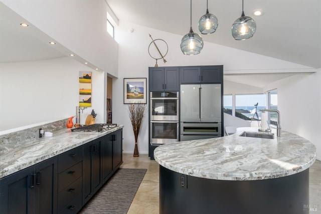 kitchen featuring sink, light stone counters, a large island with sink, pendant lighting, and appliances with stainless steel finishes