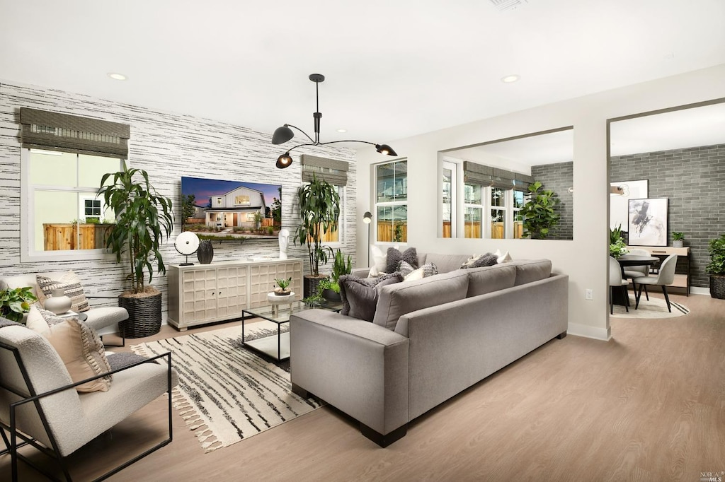 living room featuring a healthy amount of sunlight, light hardwood / wood-style floors, and a notable chandelier