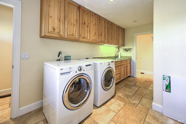 clothes washing area with cabinets, sink, and washer and clothes dryer