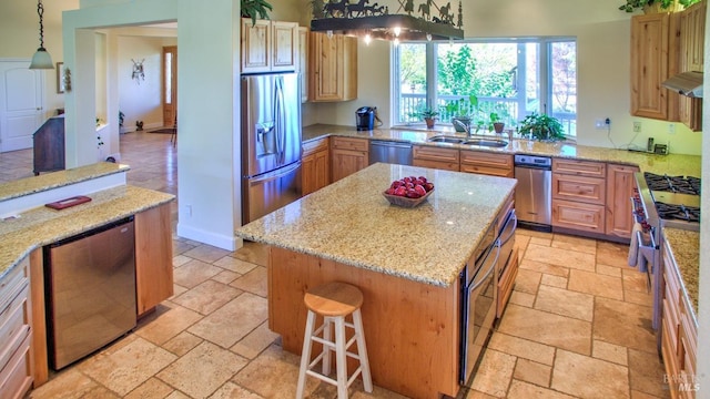 kitchen featuring sink, hanging light fixtures, a kitchen island, stainless steel appliances, and light stone countertops