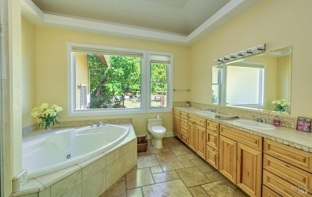 bathroom featuring vanity, tiled bath, and toilet