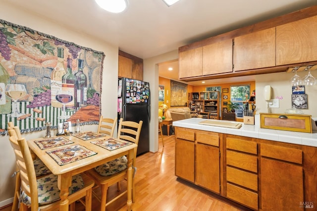 kitchen featuring freestanding refrigerator, brown cabinetry, light wood finished floors, and recessed lighting