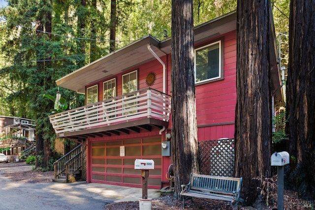 chalet / cabin featuring an attached garage, stairway, and driveway