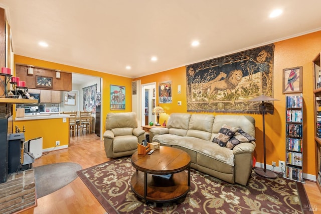 living area featuring ornamental molding, light wood-type flooring, and recessed lighting