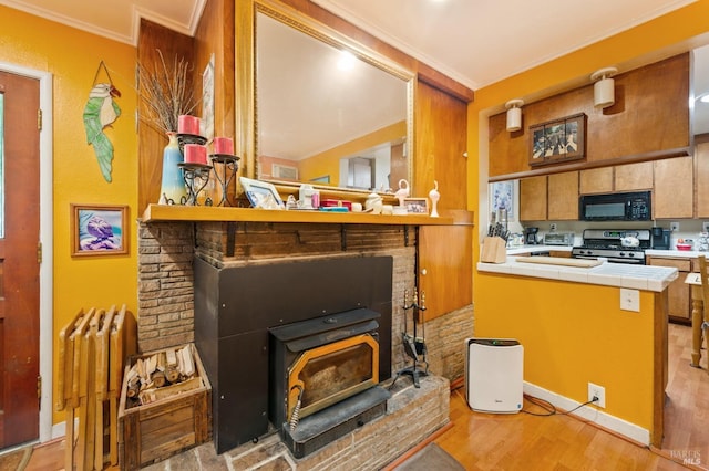 kitchen with stainless steel range with gas stovetop, tile countertops, light wood-style floors, ornamental molding, and black microwave