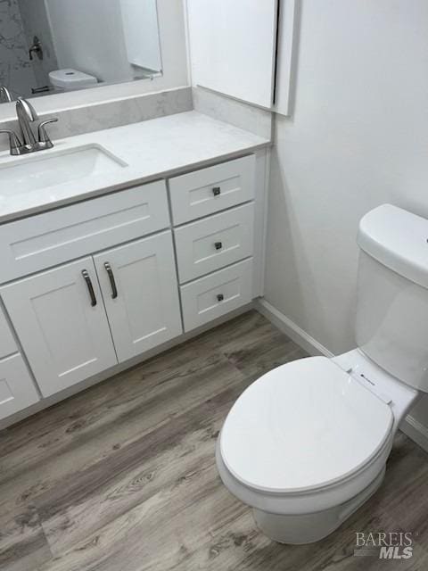 bathroom featuring wood finished floors, toilet, vanity, and baseboards
