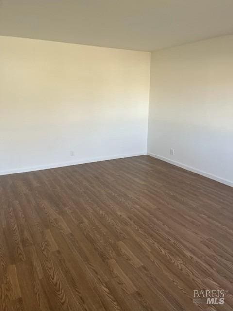 spare room featuring dark wood finished floors and baseboards