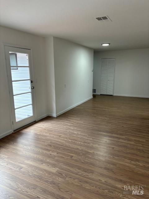 empty room featuring baseboards, visible vents, and dark wood-style flooring