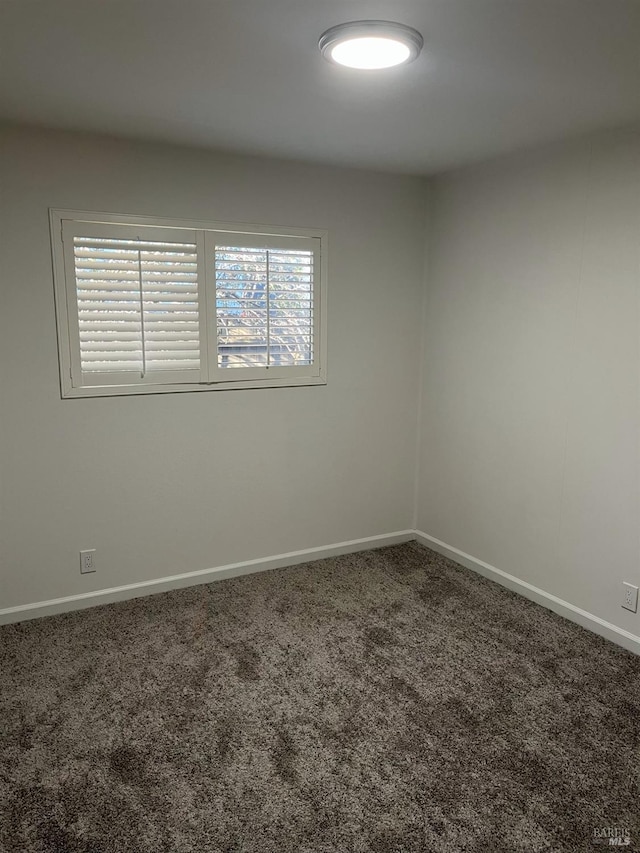 carpeted empty room featuring baseboards
