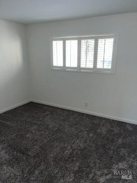 carpeted empty room featuring baseboards