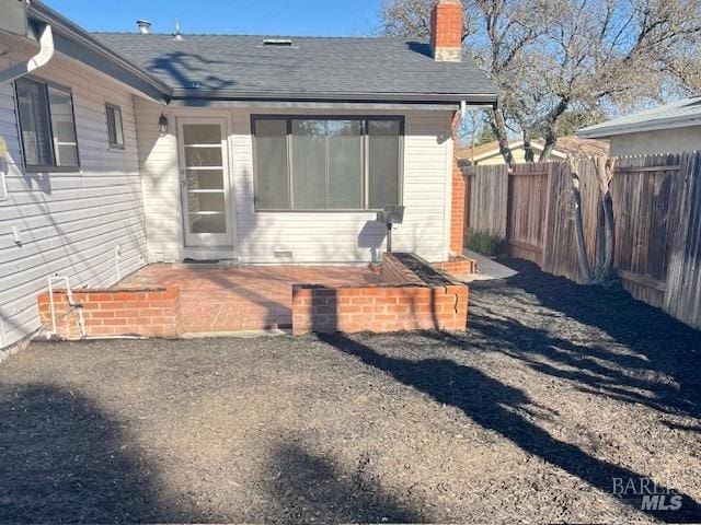 rear view of house with fence, a chimney, and a shingled roof